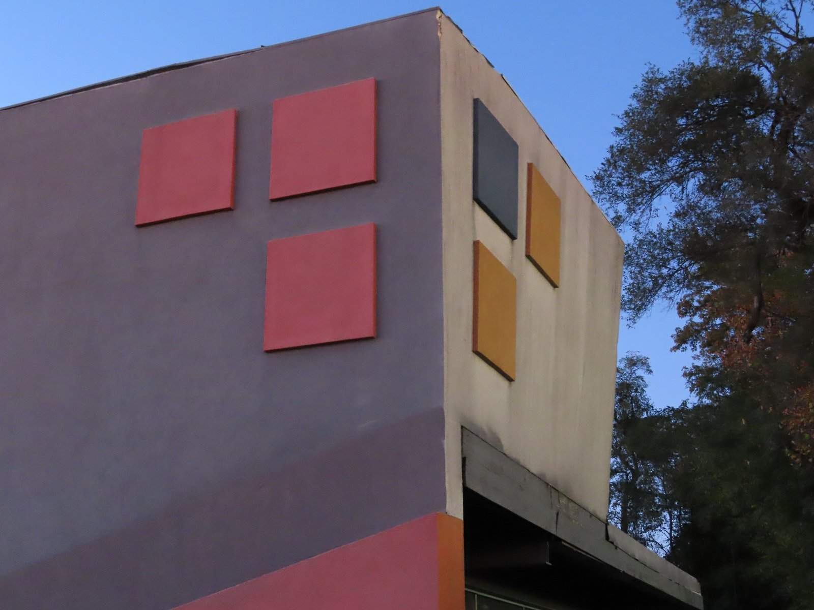 Front corner of commercial building with gray paint and more pink color blocks.